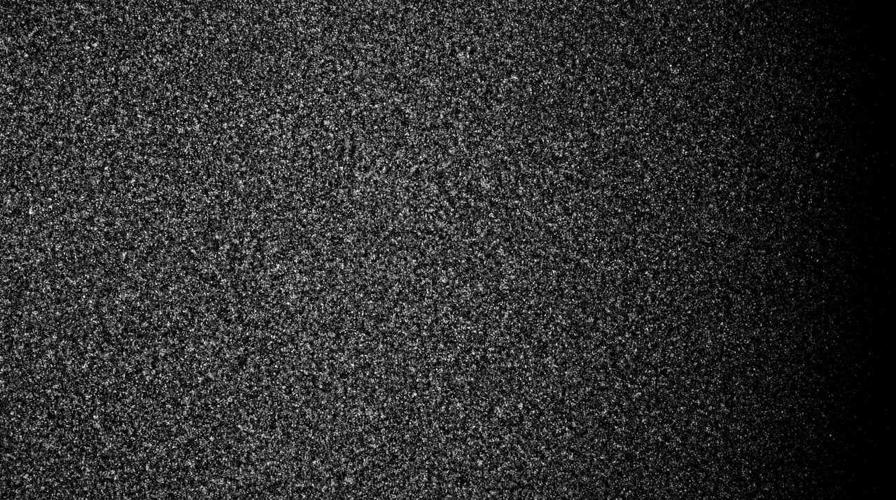 A dense, monochromatic film grain texture with subtle light falloff on the right.