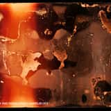 Intense analog film burn texture overlay featuring a glowing bright orange and red light leak with melted, decayed film emulsion edges and high contrast.