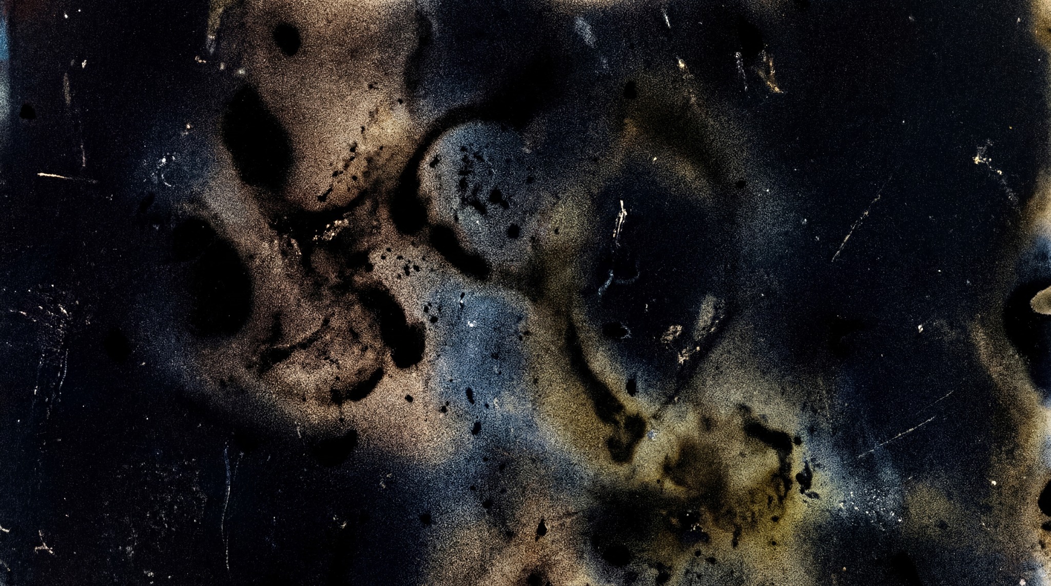 A dark, abstract texture with organic shapes and scattered light specks, resembling an analog film burn.
