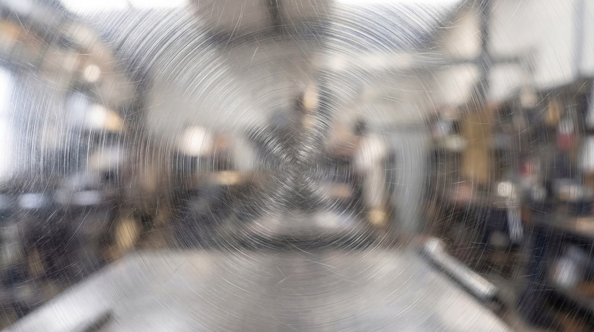 Close-up view of a metal surface featuring distinct radial circular scratch patterns and a brushed finish