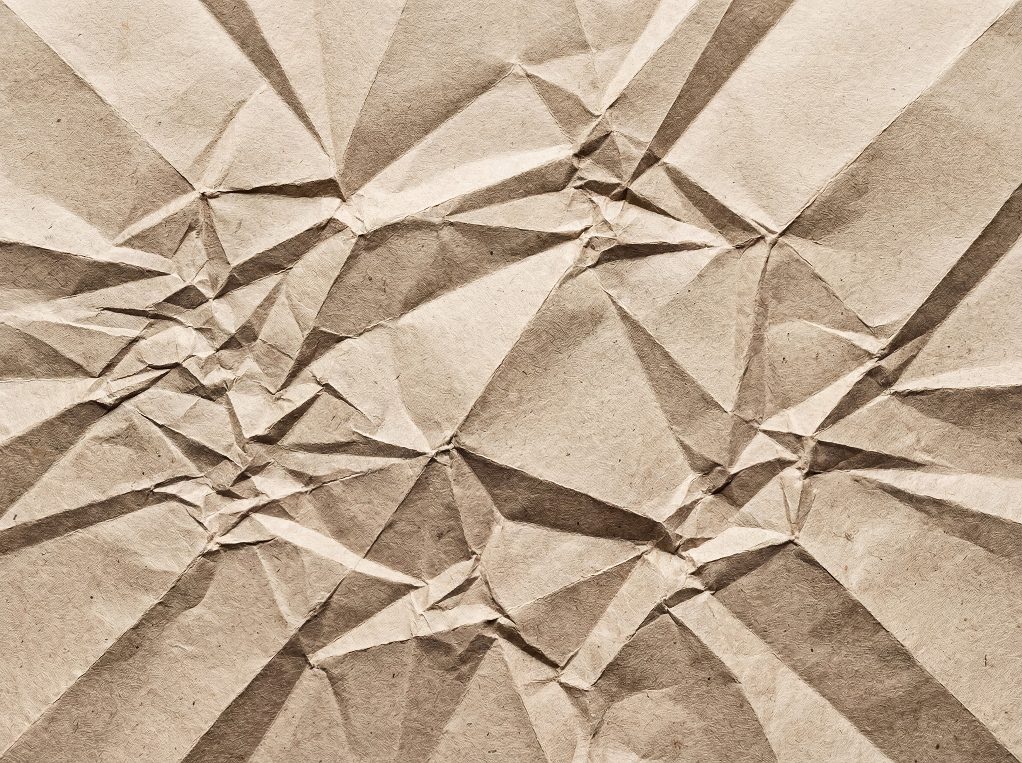 A detailed, high-resolution texture of heavily crumpled brown kraft paper, showcasing sharp folds and deep shadows.