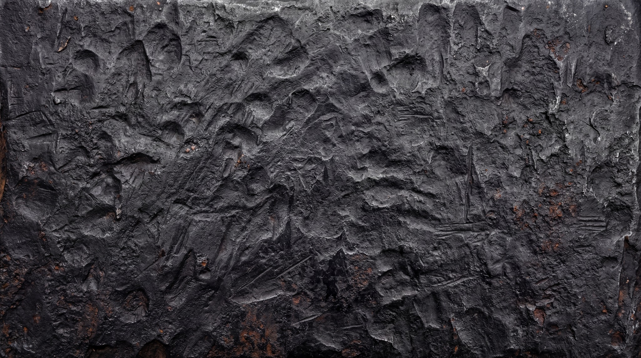 A close-up of a raw forged steel surface featuring deep impact marks, heavy indentations, and coarse dark grey metal pitting.