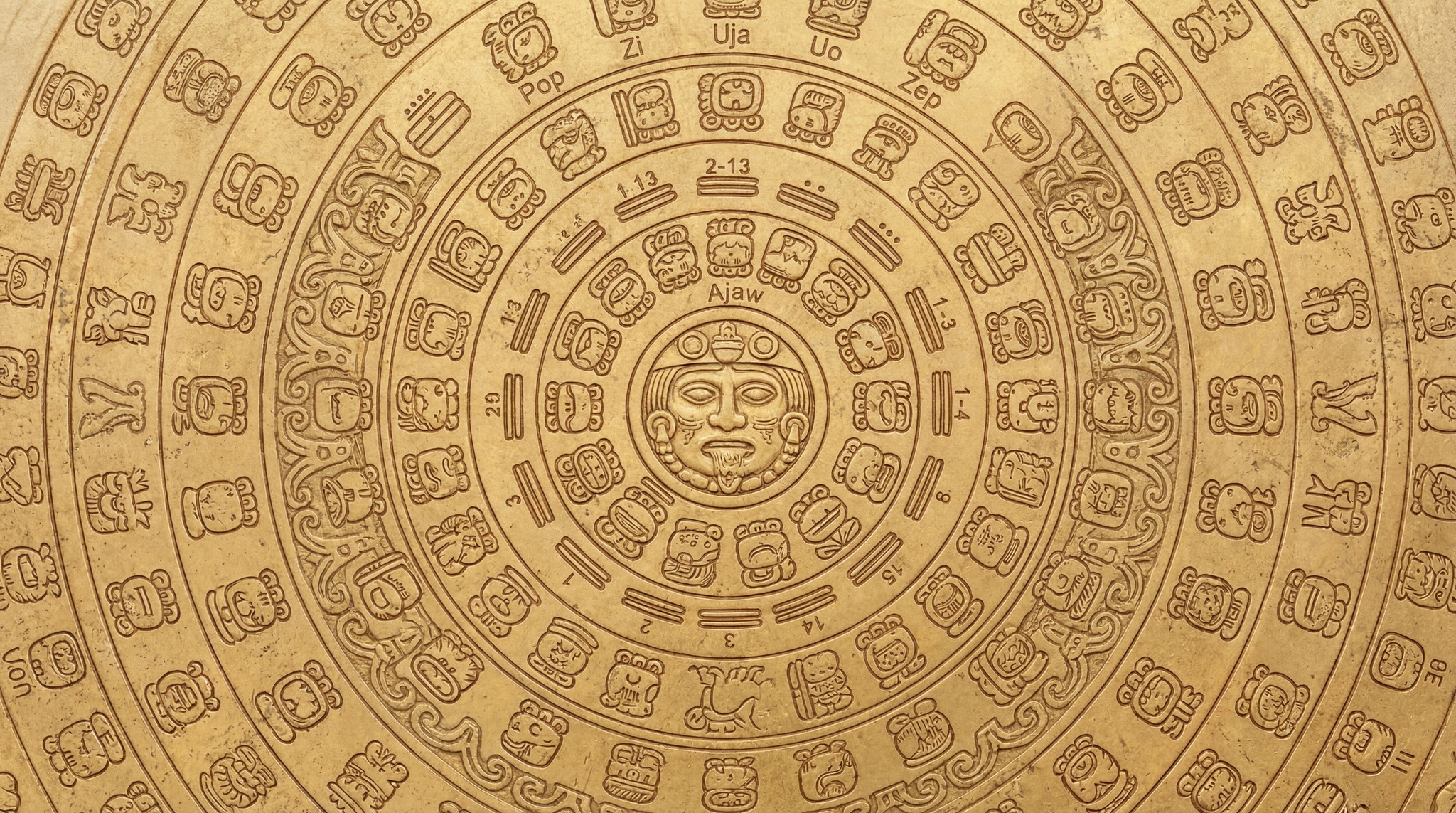 Close-up of an ornate, circular Mayan calendar carved into a textured gold surface, featuring glyphs and numerical elements.