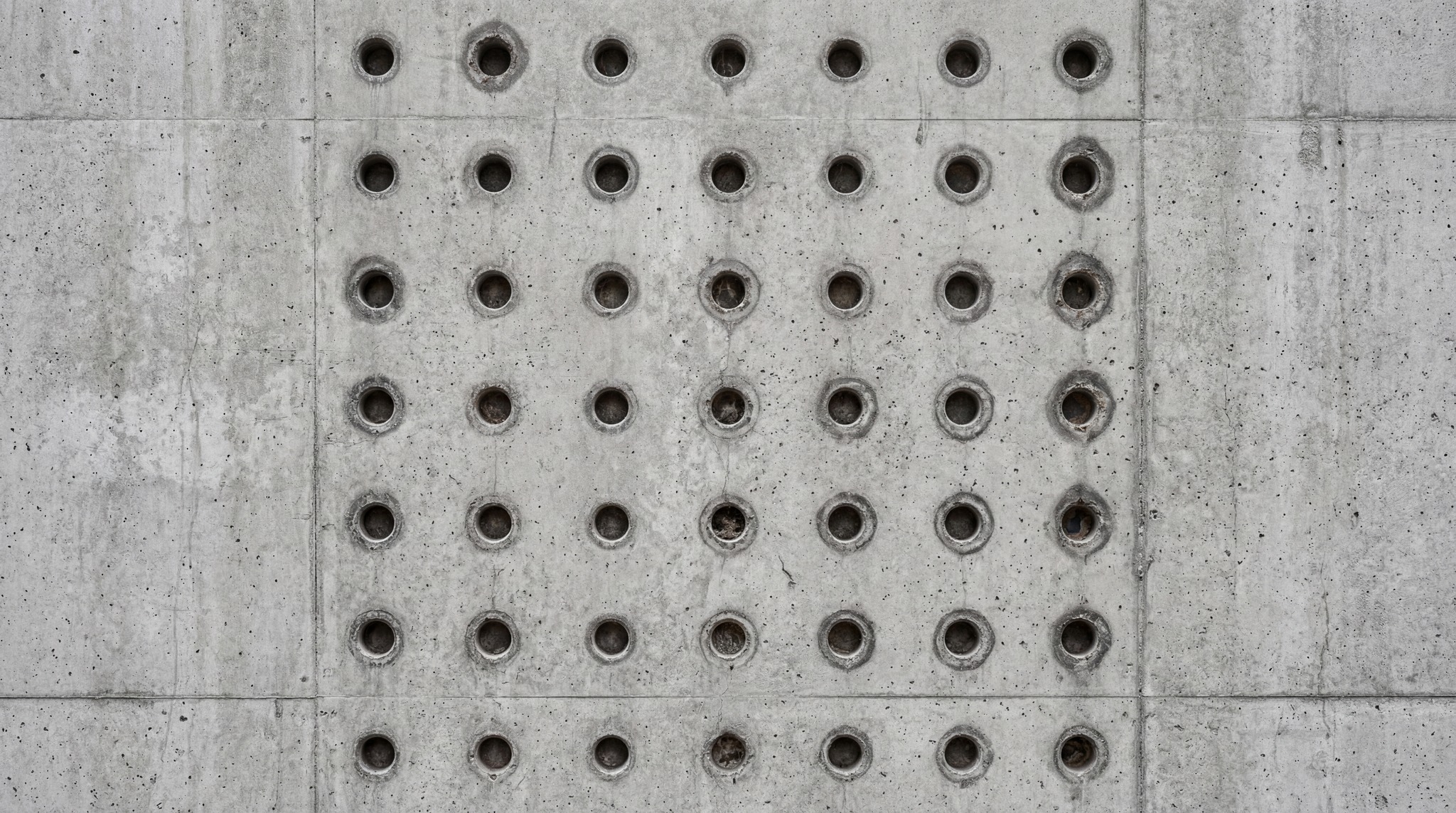 A seamless 4K texture of raw brutalist concrete with a grid of circular indentations.