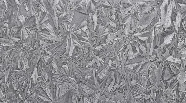 Close-up view of a galvanized steel sheet featuring a distinctive spangle crystal pattern in shades of grey.