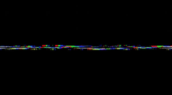 A horizontal line of colorful digital glitch artifacts with red, green, and blue blocks on a black background.