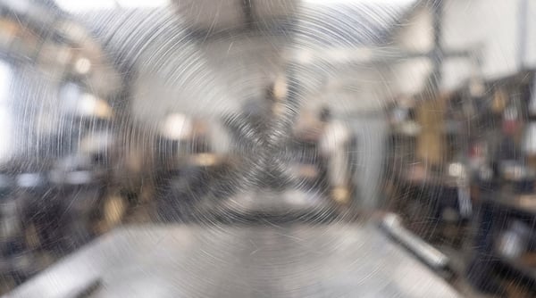 Close-up view of a metal surface featuring distinct radial circular scratch patterns and a brushed finish