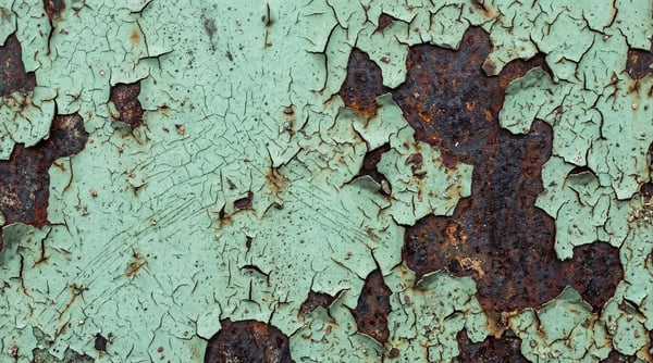 High-resolution texture of peeling mint green paint revealing dark rusted metal beneath.