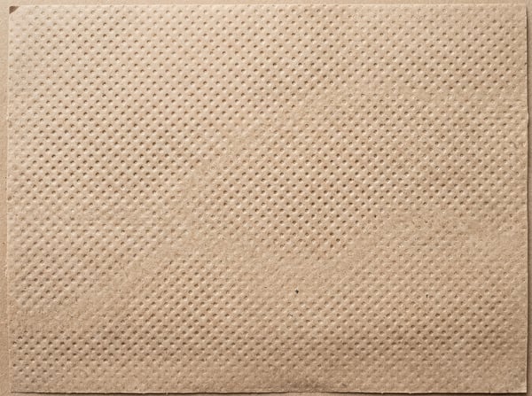 A full-frame, top-down view of a textured brown recycled paper surface with a regular pattern of small indentations.