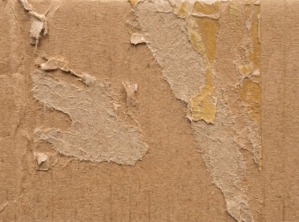 Close-up of torn brown cardboard texture with visible adhesive residue.
