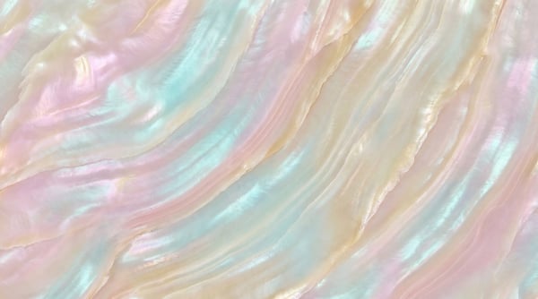 Close-up of iridescent marble with soft pink, cyan, and pale yellow swirling patterns.