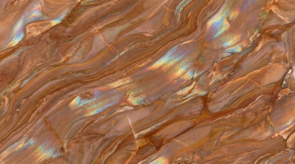 A close-up of a brown marble texture with swirling patterns and iridescent rainbow highlights.