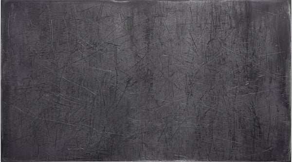 A dark, raw steel surface featuring heavy linear scratches and industrial wear across the entire metallic texture.