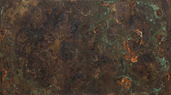 A dark, heavily corroded metal surface with deep pitting and patches of green patina.